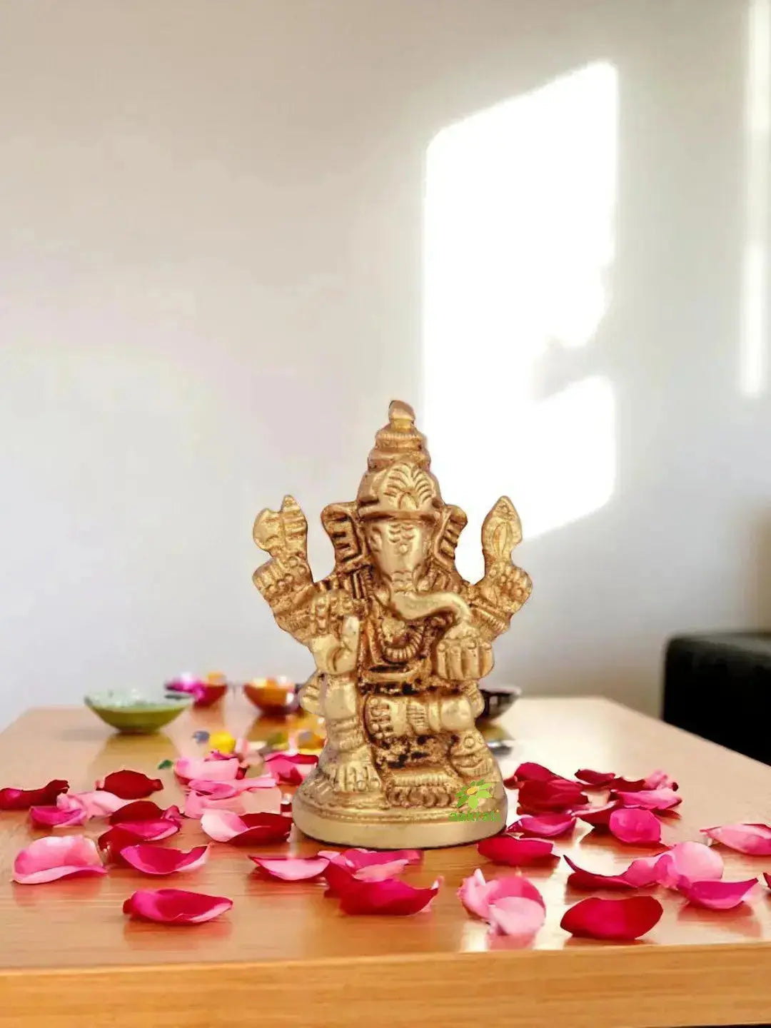 A polished brass Lord Ganesha statue placed on a minimal console table, serving as a central focal point in a clean, well-balanced interior with neutral tones and soft lighting.