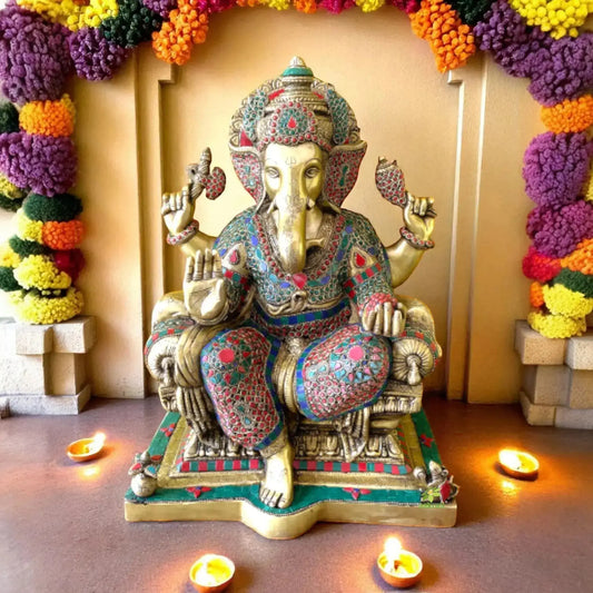 Turquoise brass Ganesha figurine with intricate carvings, depicting the Hindu deity seated gracefully, adorned with ornate jewelry and a crown, finished in a patina that highlights blue-green tones against warm metallic accents.