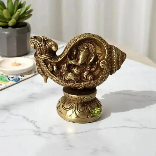Decorative brass Ganesha resting in a shankh representing harmony, wisdom, and protection