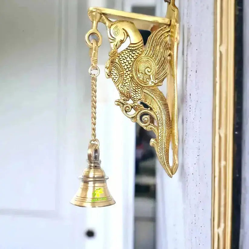 Traditional brass peacock hanging bell used as an elegant home décor piece in an entryway