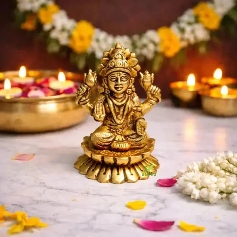 A brass Lakshmi idol portrays the Goddess seated on a sacred lotus, symbolizing purity and spiritual grace. Crafted with a radiant golden finish, she is adorned with fine ornaments, exuding prosperity and elegance. 